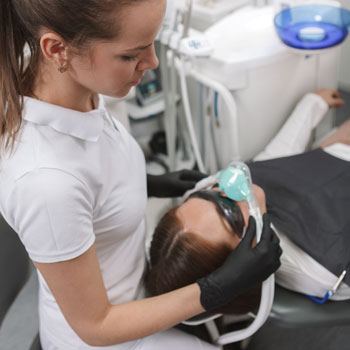 Dentist putting on inhalation sedation mask on her patient