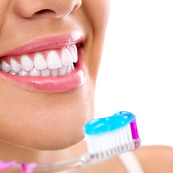 Woman with healthy teeth holding a tooth-brush